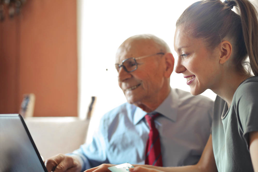 Young woman and older man happily looking at laptop